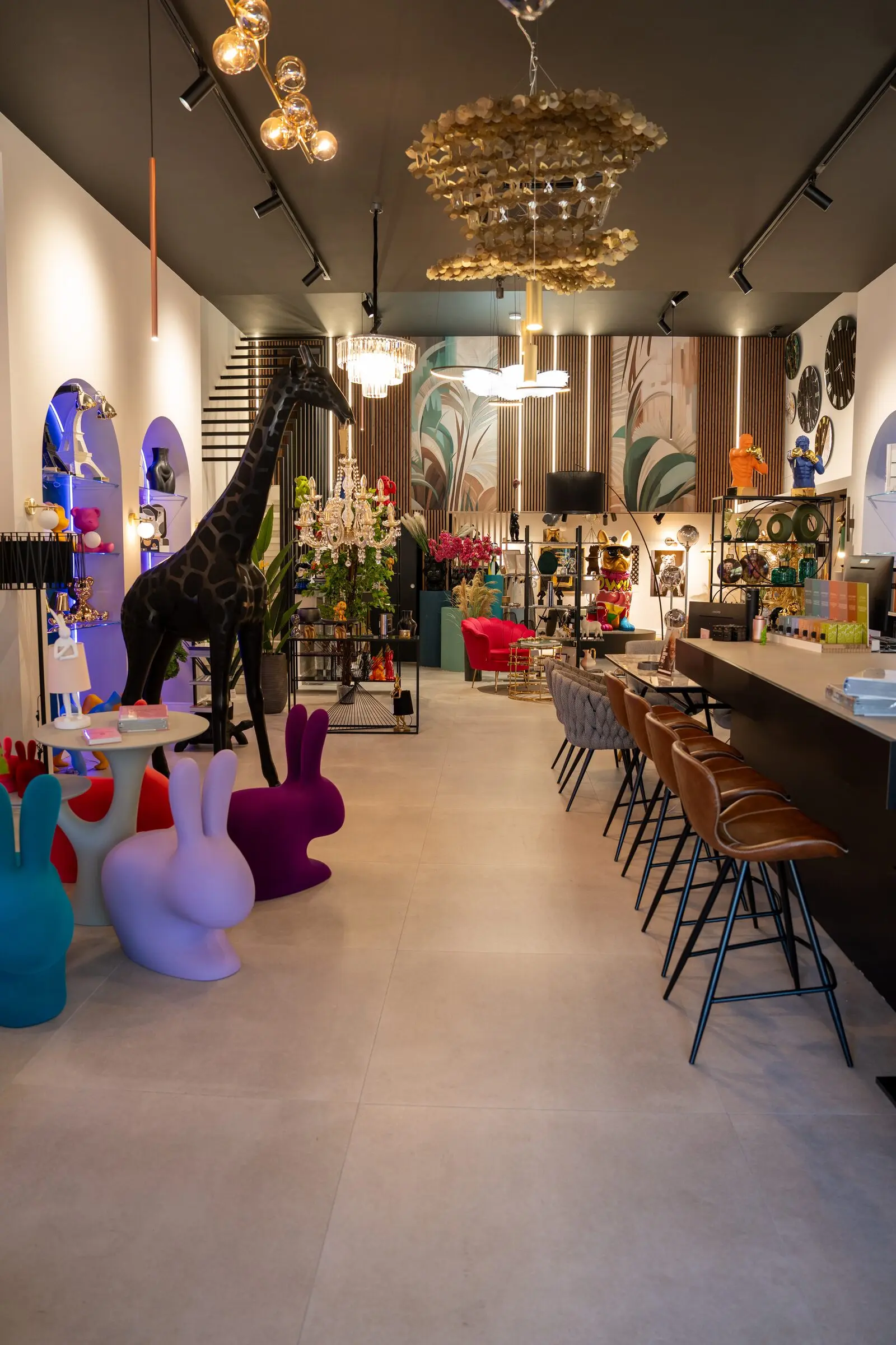 Interno dello store Home Design: una giraffa nera a grandezza naturale, sedute a forma di coniglio e un lampadario dorato.